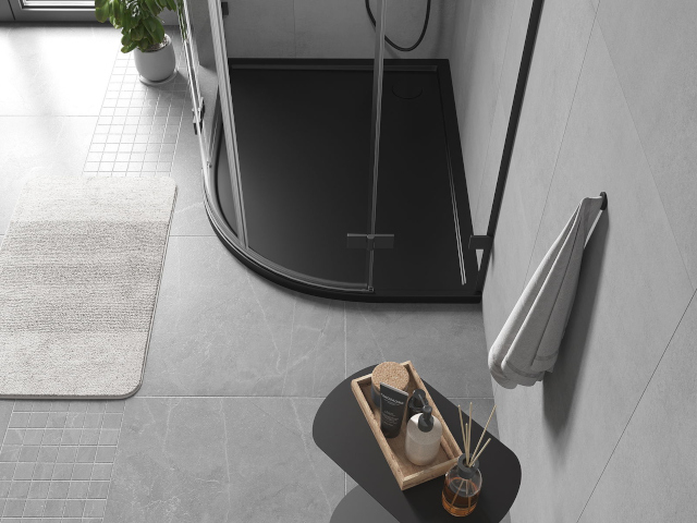 Melns asimetrisks pusapaļš dušas paliktnis vannas istabā