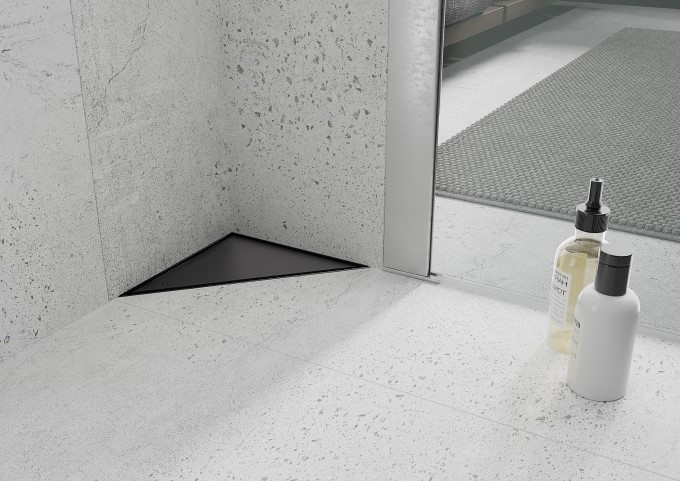 Melns grīdas notekas pelēkā vannas istabā